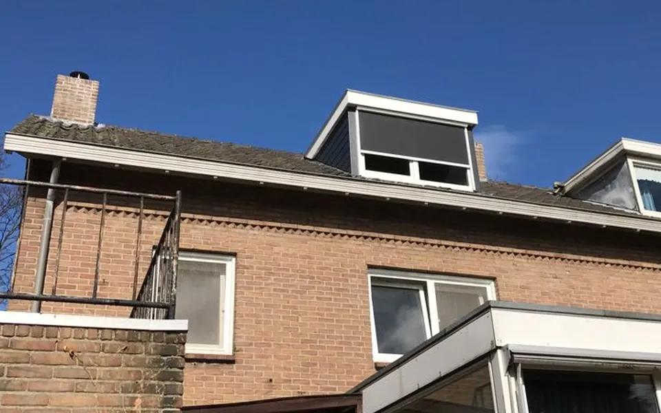Na: dezelfde woning met een nieuwe dakkapel met donkere zijwangen en een rolluik