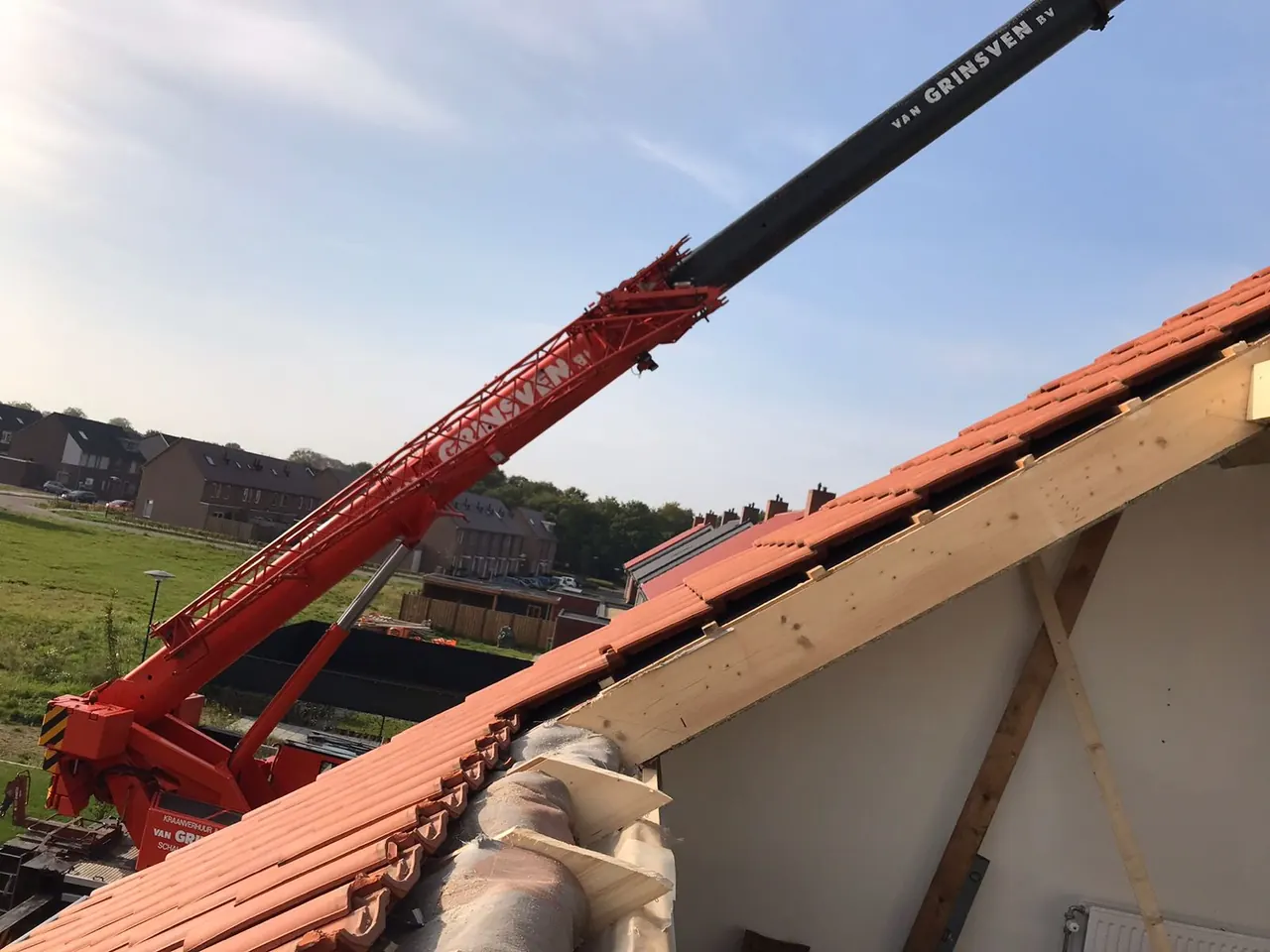 Kraan tilt een dakkapel op een open dak van een nieuwbouwwoning