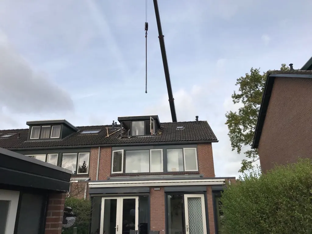 Kraan bij een woning waar de oude dakkapel wordt vervangen
